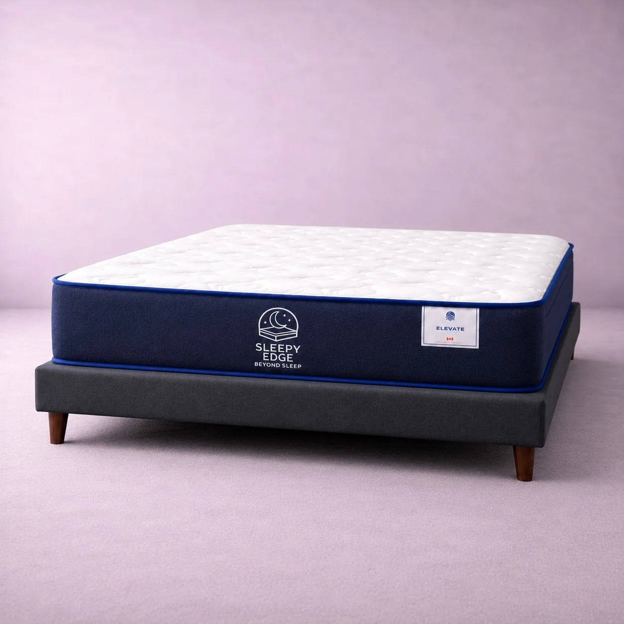 A Sleepy Edge Elevate mattress with a white quilted top and navy side panel, resting on a dark upholstered platform bed frame with wooden legs.